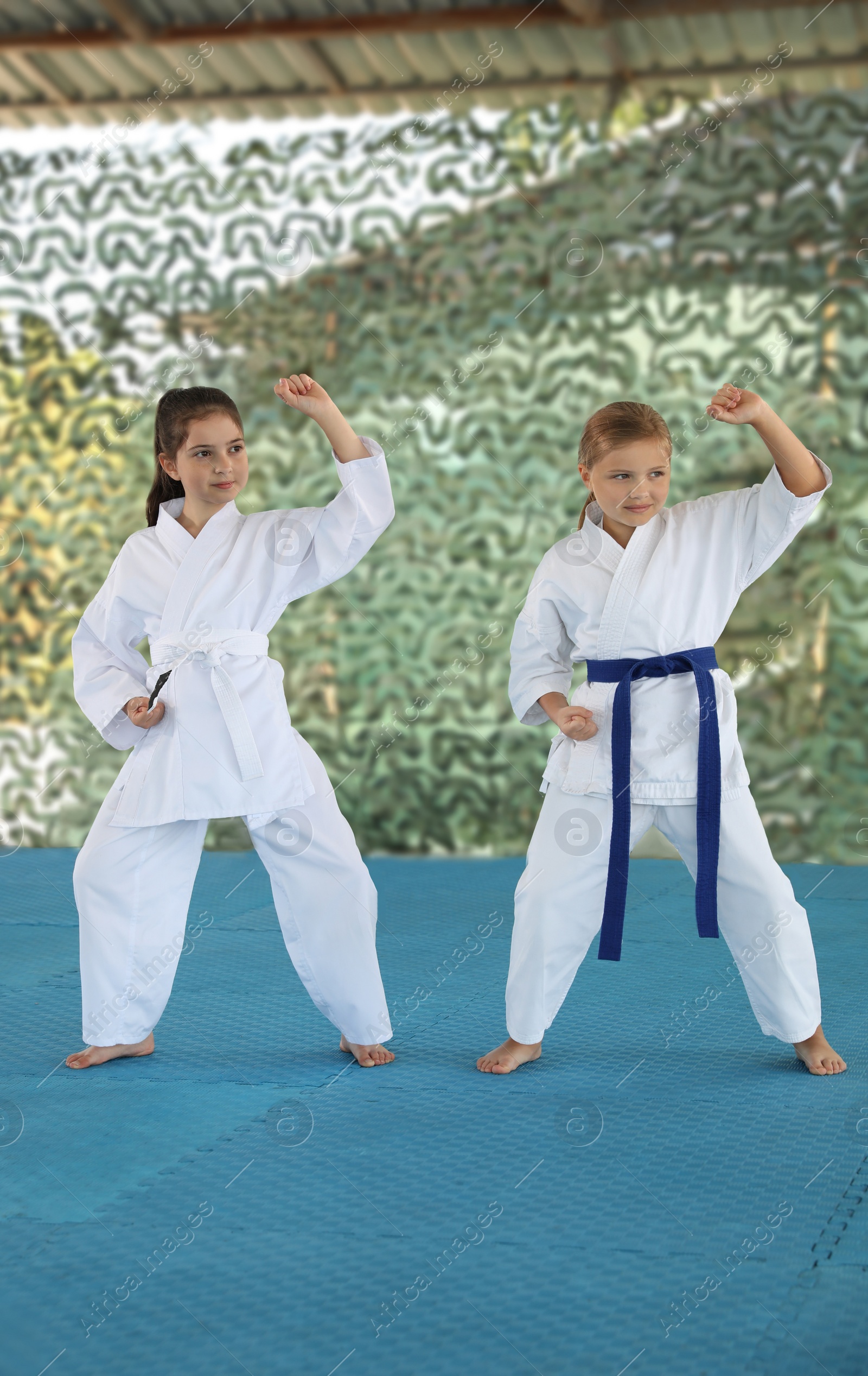 Photo of Children in kimono practicing karate on tatami outdoors