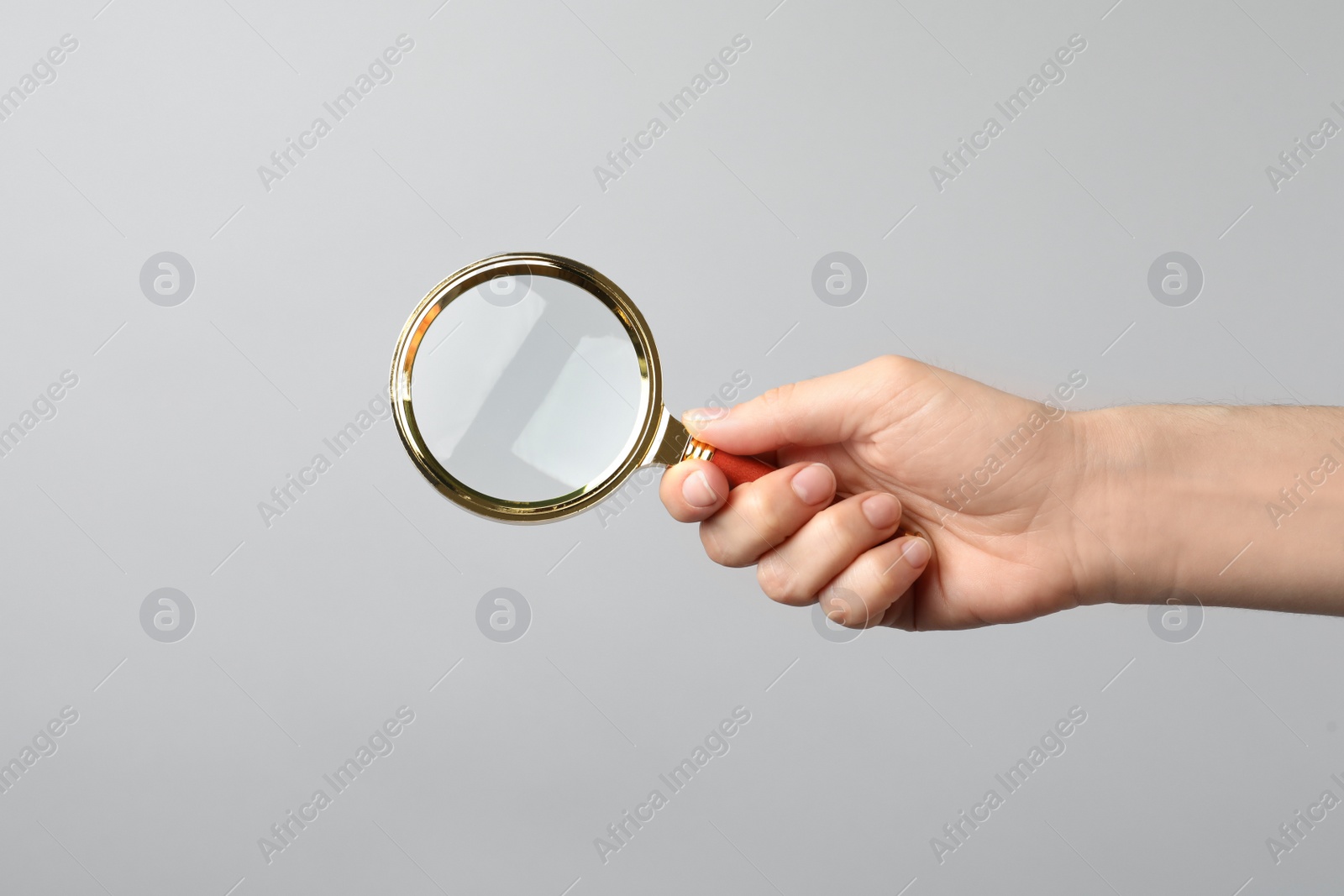 Photo of Woman holding magnifying glass on grey background, closeup. Find keywords concept