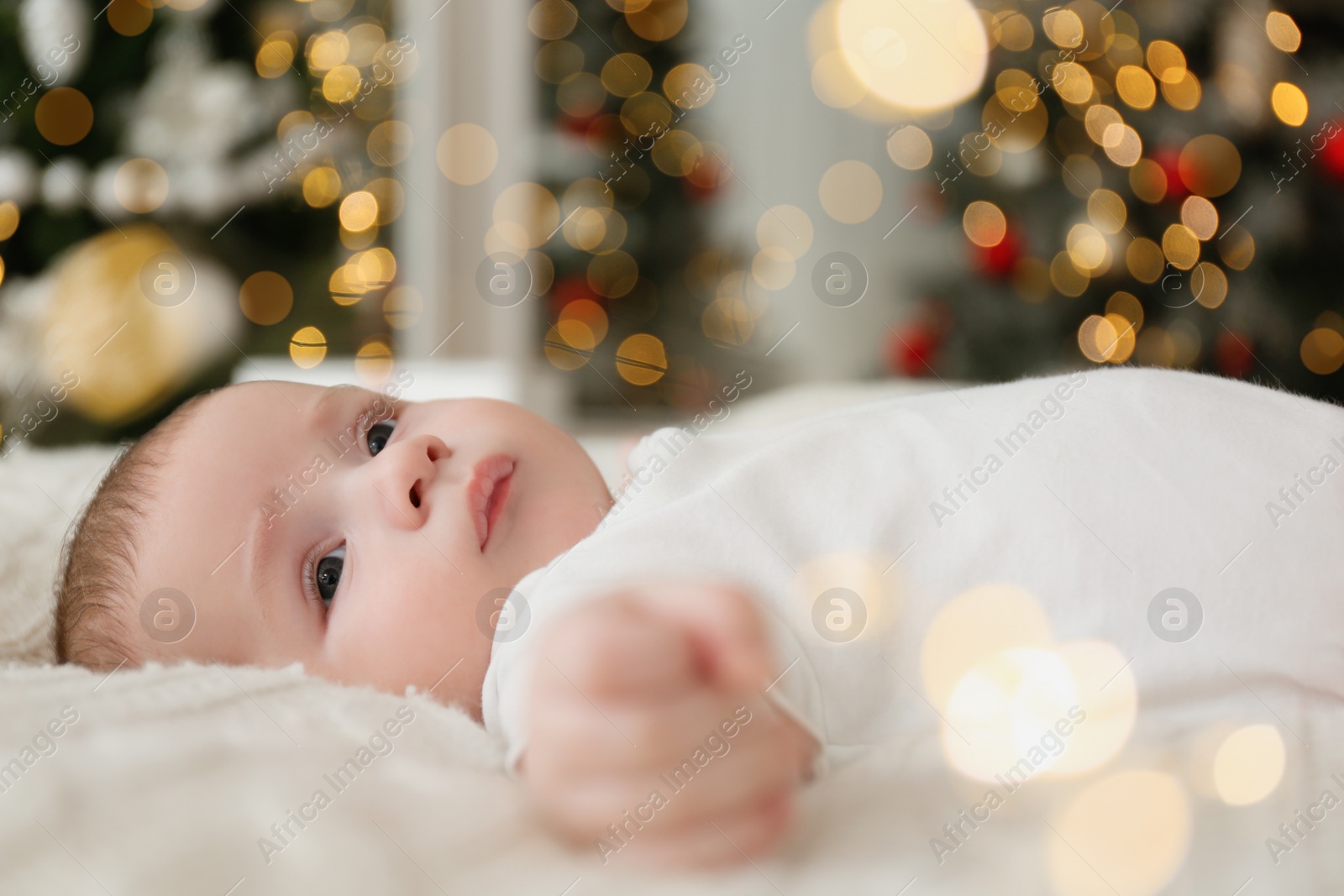 Photo of Cute little baby on blanket in room with Christmas tree