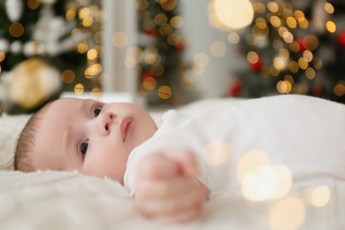 Cute little baby on blanket in room with Christmas tree