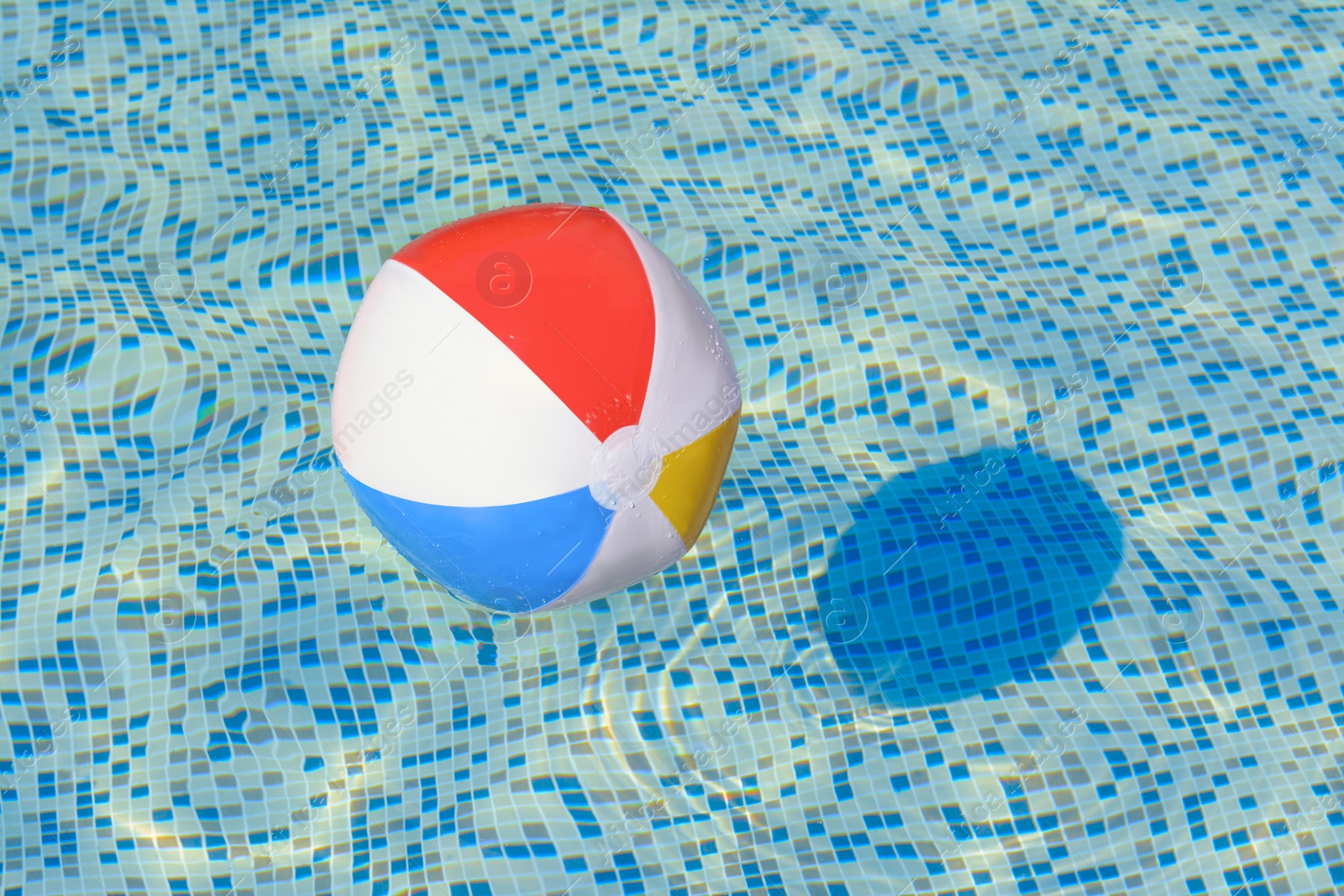 Photo of Inflatable beach ball floating in swimming pool, space for text