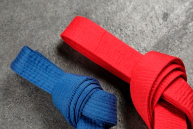 Colorful karate belts on gray textured background, top view