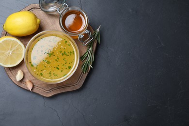 Bowl of lemon sauce and ingredients on dark table, top view with space for text. Delicious salad dressing