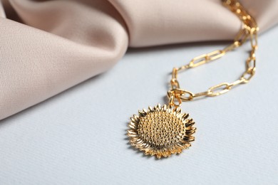 Elegant necklace and beige cloth on white table, closeup