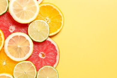 Photo of Different sliced citrus fruits on yellow table, top view. Space for text