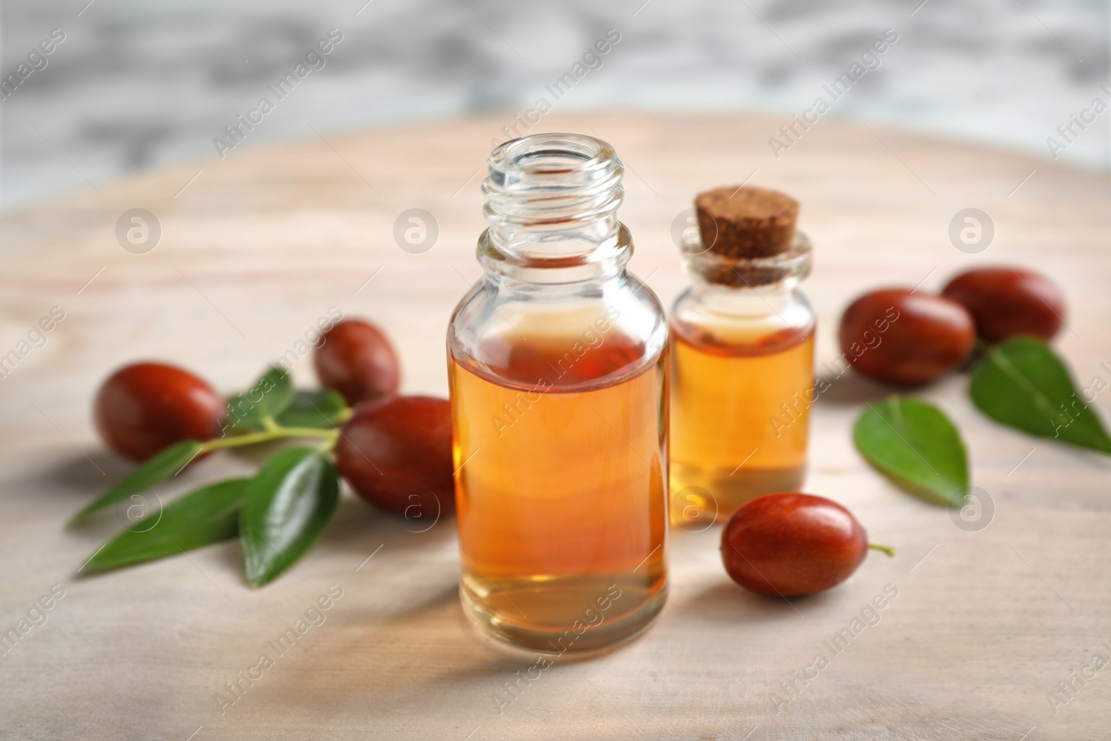 Photo of Glass bottles with jojoba oil and seeds on light table