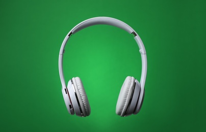 Stylish modern headphones with earmuffs on color background