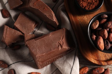 Pieces of tasty milk chocolate, cocoa beans and powder on table, flat lay