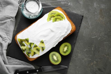 Delicious homemade yogurt cake with kiwi and cream on gray table, flat lay