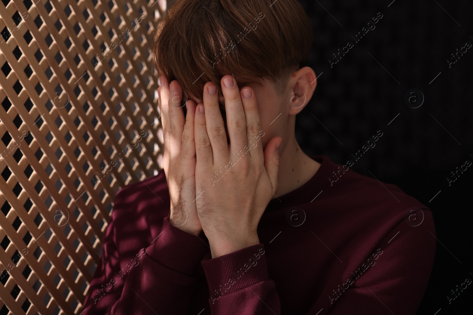 Photo of Upset man near wooden partition during confession in booth