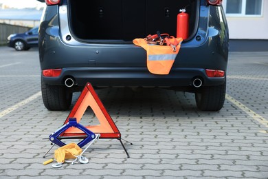 Photo of Emergency warning triangle and safety equipment near car, space for text