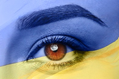 Image of Double exposure of national flag and young woman, closeup of eye. Stop war in Ukraine