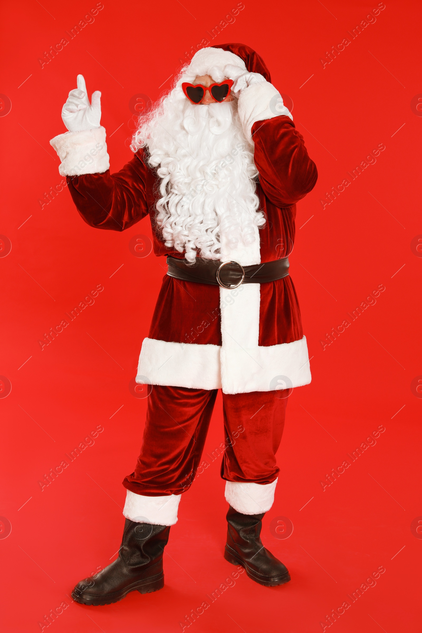 Photo of Authentic Santa Claus wearing sunglasses on red background