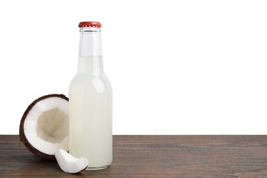 Delicious kombucha in glass bottle and coconut on wooden table against white background, space for text