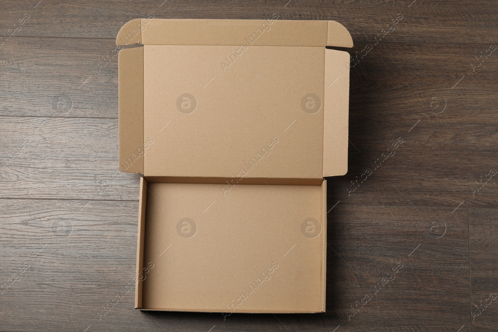 Photo of Empty open cardboard box on wooden table, top view