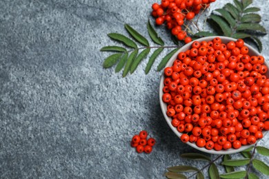 Photo of Fresh ripe rowan berries and leaves on grey table, flat lay. Space for text