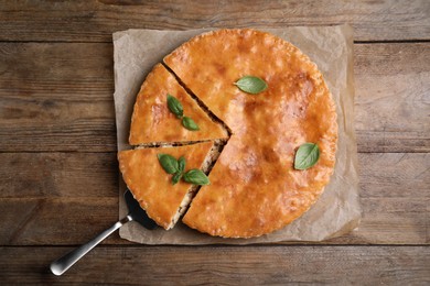 Photo of Delicious pie with meat and basil on wooden table, top view