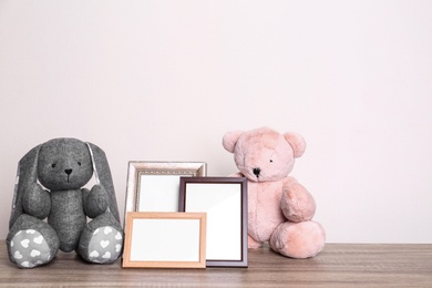 Photo of Photo frames and adorable toys on table against light background, space for text. Child room elements