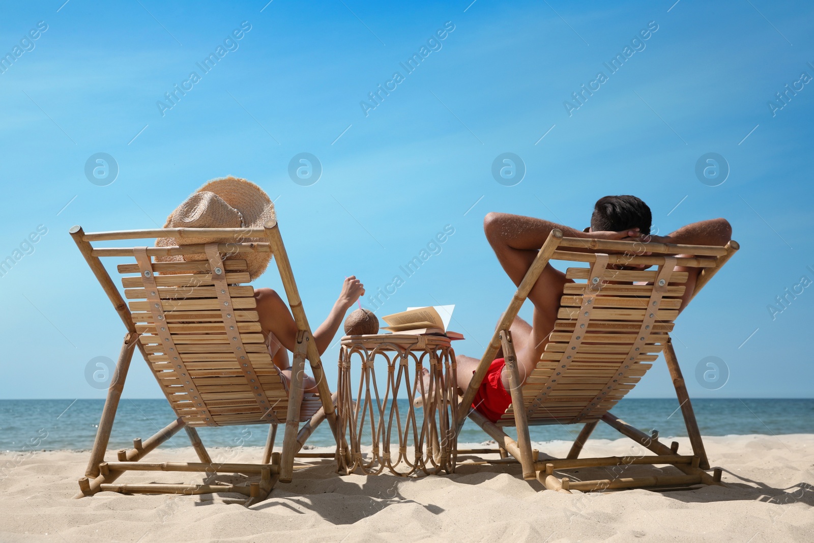 Photo of Couple resting in wooden sunbeds on tropical beach