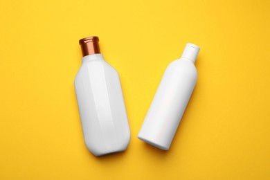 Photo of Bottles of shampoo on yellow background, flat lay