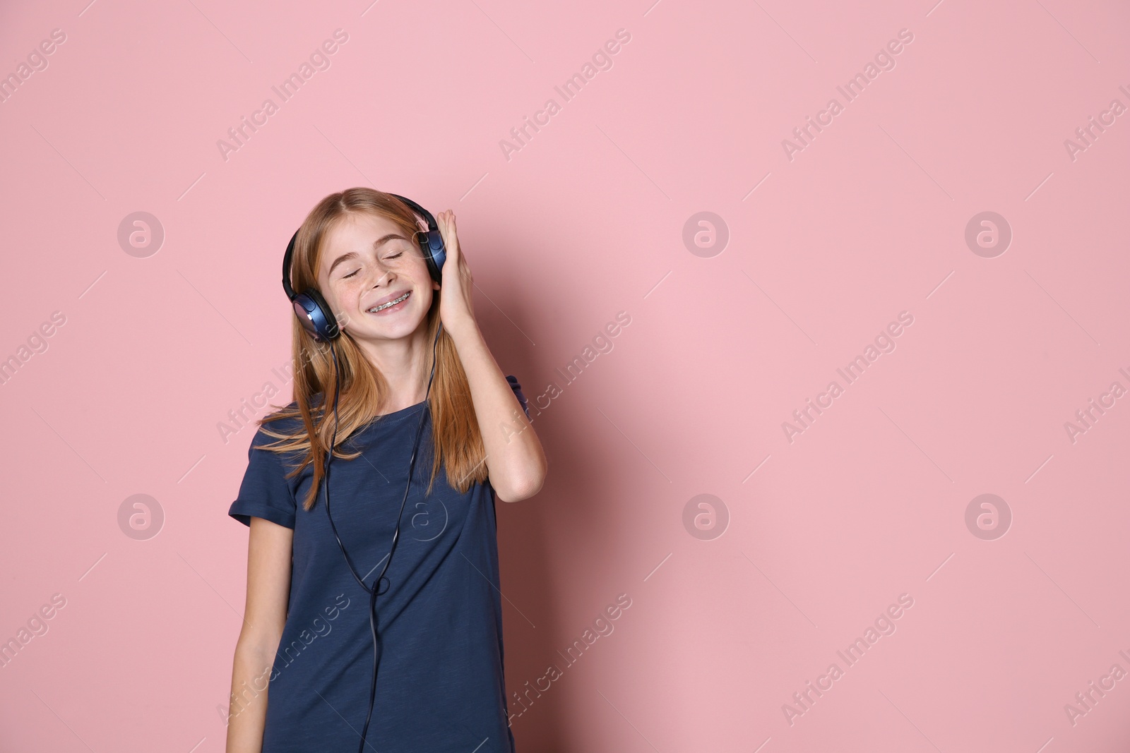 Photo of Teen girl listening to music with headphones on color background, space for text