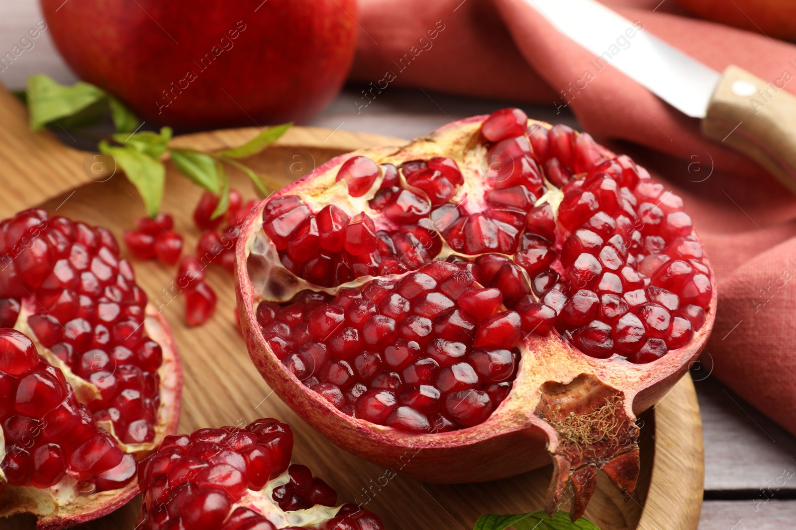 Photo of Fresh pomegranates and green leaves on table, closeup