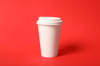 Takeaway paper coffee cup on red background