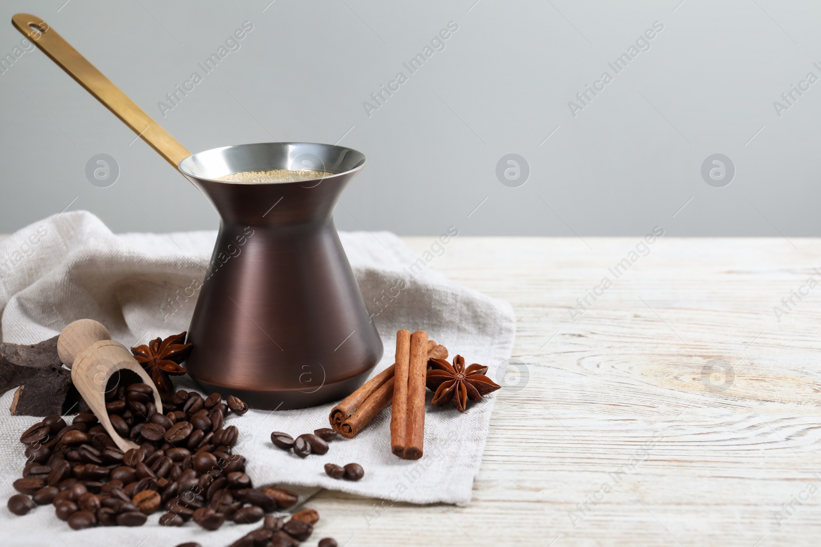 Photo of Hot turkish coffee pot, beans and spices on white wooden table, space for text
