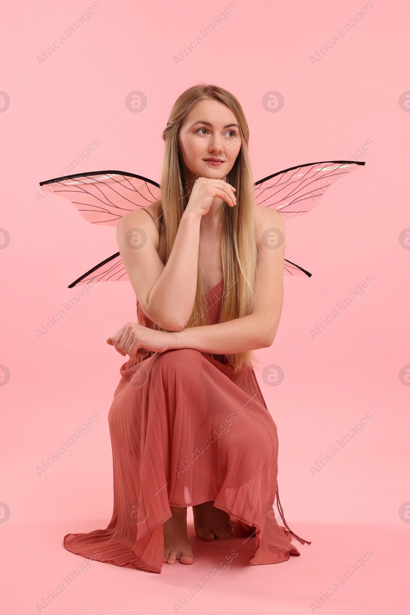 Photo of Beautiful girl in fairy costume with wings on pink background