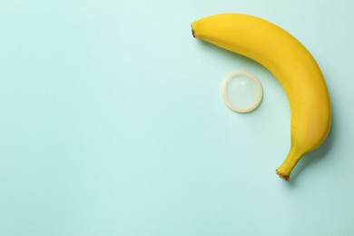 Photo of Banana and condom on turquoise background, flat lay with space for text. Safe sex concept