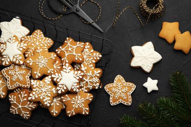 Tasty Christmas cookies with icing, scissors and spool of thread on black table, flat lay