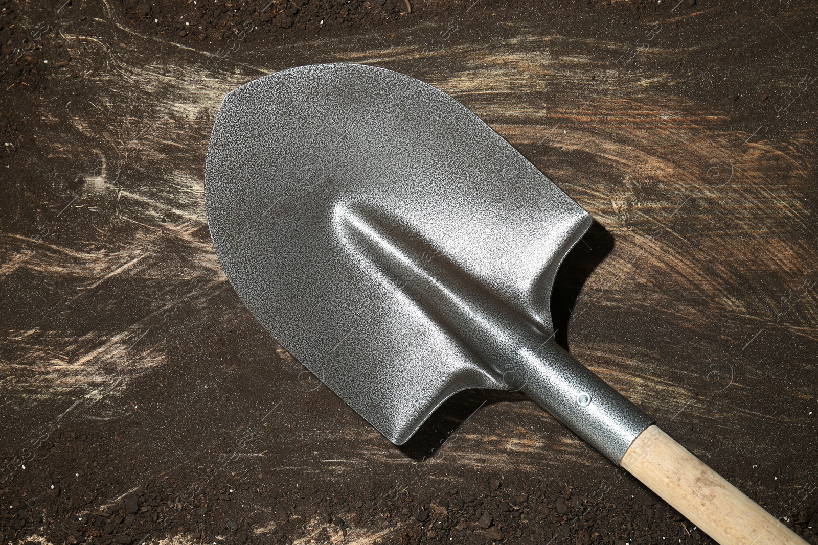 Metal shovel on dirty wooden surface, top view Photo of Metal shovel on dirty wooden surface, top view