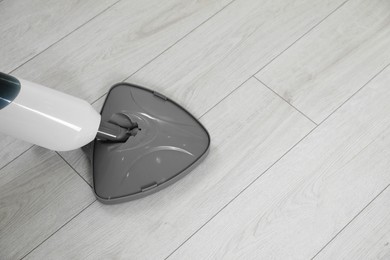 Photo of Cleaning floor with steam mop at home, top view. Space for text