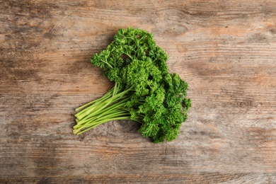 Photo of Bunch of fresh green parsley on wooden table, top view