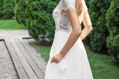 Photo of Gorgeous bride in beautiful wedding dress outdoors, closeup