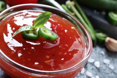 Photo of Spicy chili sauce in glass bowl on table, closeup