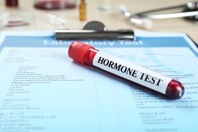 Photo of Hormone test. Sample tube with blood and laboratory form on table, closeup