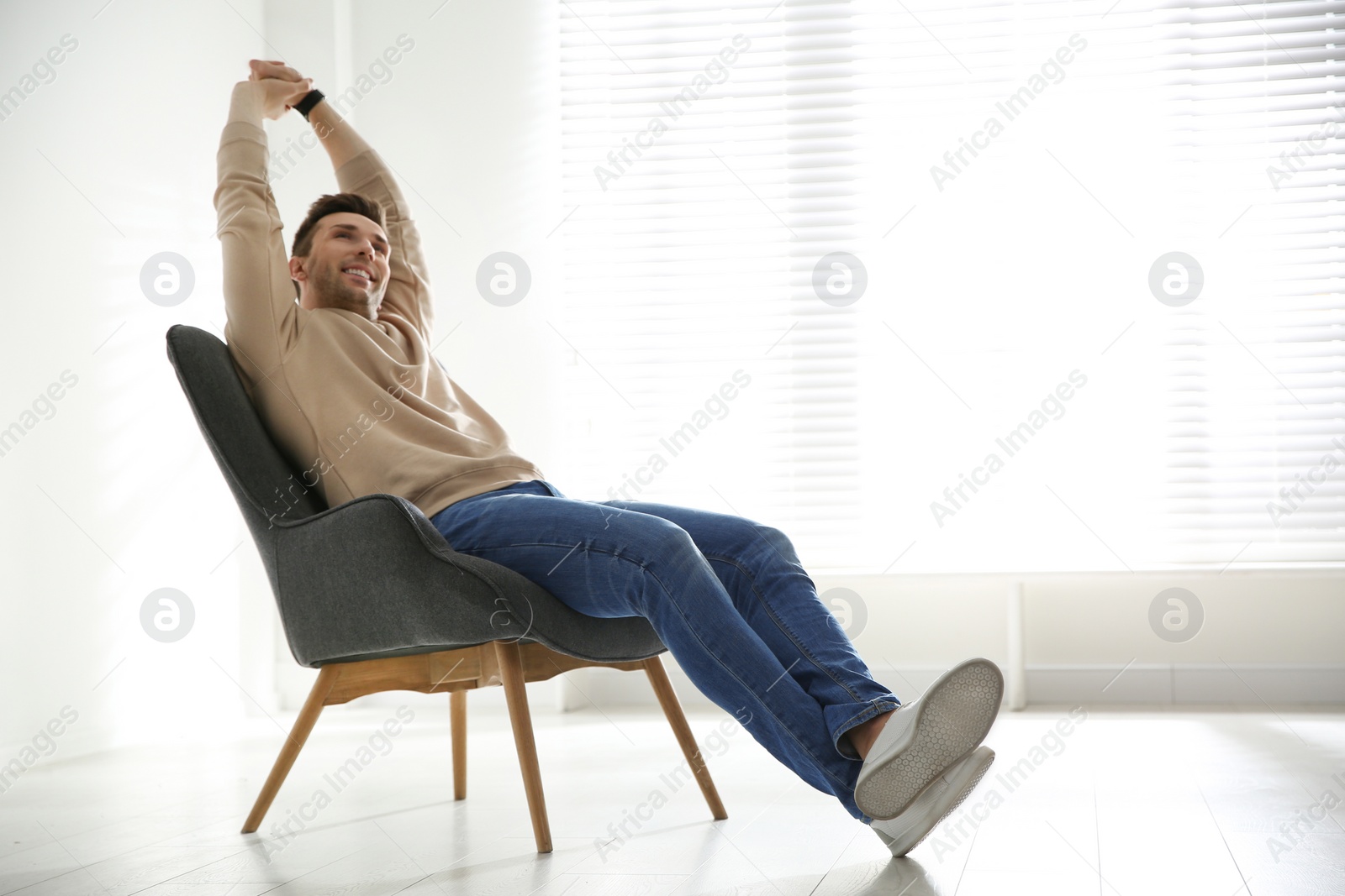 Photo of Young man relaxing in armchair near window at home. Space for text