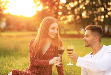 Photo of Happy young couple with wine having picnic in park