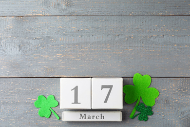 Flat lay composition with wooden block calendar on grey background, space for text. St. Patrick's Day celebration