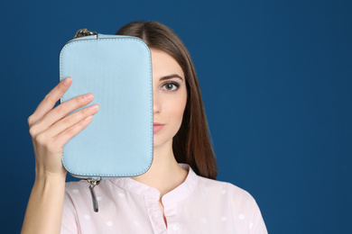 Beautiful young woman with stylish bag on blue background