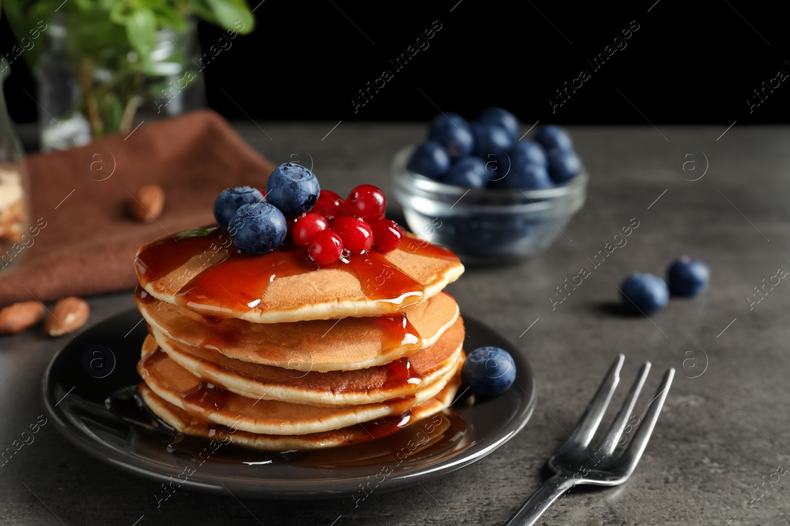 Photo of Stack of tasty pancakes with berries and syrup on table