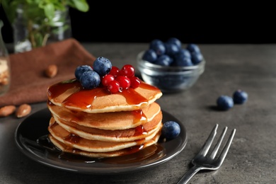 Photo of Stack of tasty pancakes with berries and syrup on table