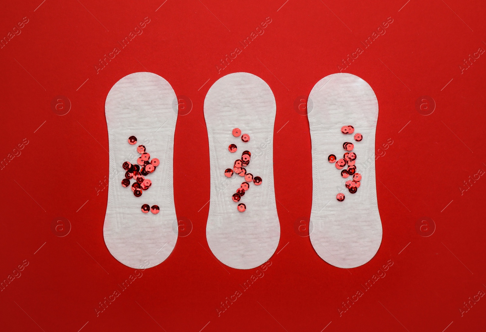 Photo of Sanitary pads with sequins on red background, flat lay. Menstrual cycle