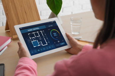 Image of Energy efficiency home control system. Woman using tablet to set indoor temperature, closeup