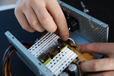 Photo of Male technician repairing power supply unit at table, closeup