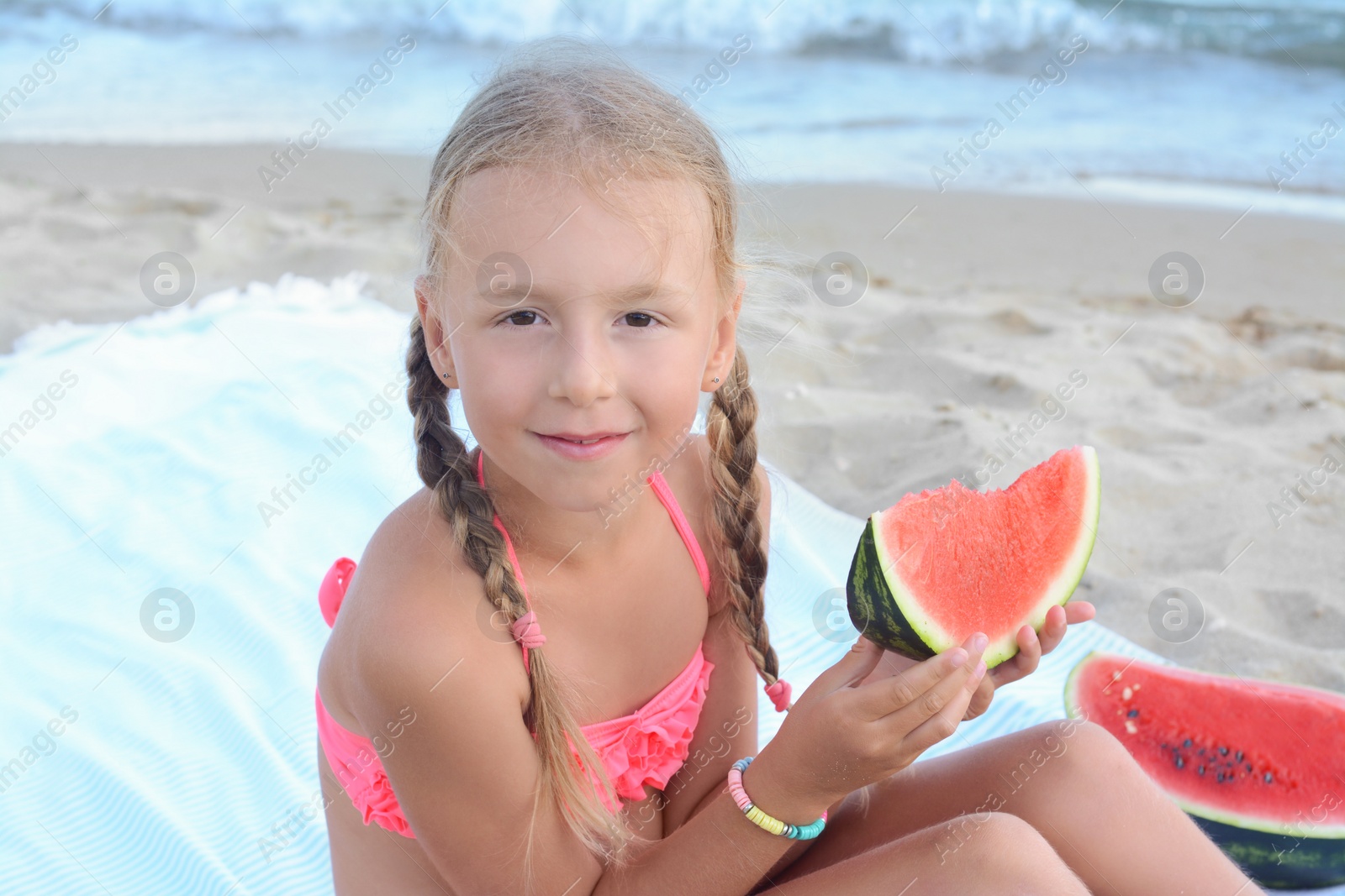 Photo of Cute little girl eating juicy watermelon on beach