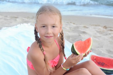 Cute little girl eating juicy watermelon on beach