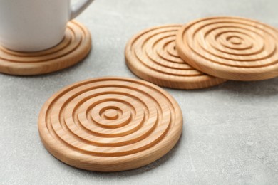 Stylish wooden cup coasters on light grey table