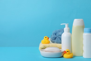 Baby cosmetic products, bath ducks, sponge and towel on light blue background. Space for text